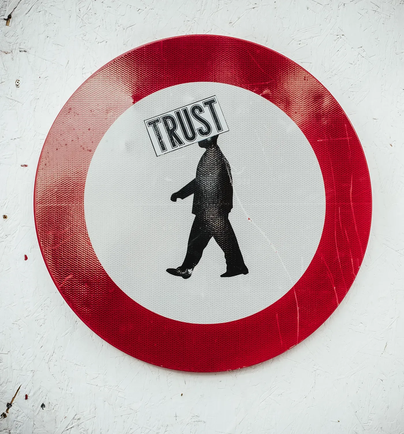 pedestrian walking road sign with a sticker saying trust plastered over the figure