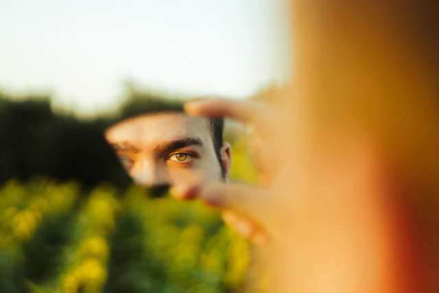 person looking at the camera through a mirror piece